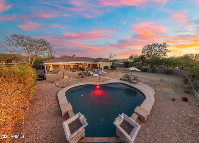 pool at dusk featuring a patio