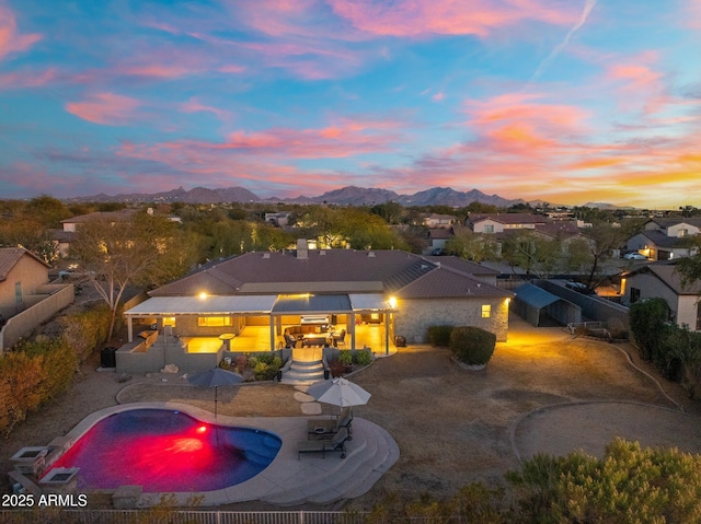 pool at dusk featuring a mountain view and a patio area