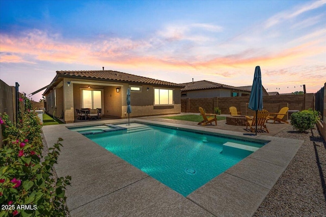 11951 W Wier Ave, Avondale, AZ 85323 - pool at dusk with an outdoor fire pit, a patio area, a fenced backyard, and a pool with connected hot tub