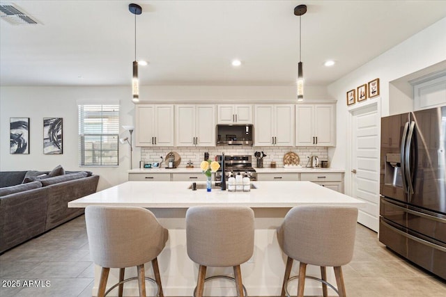 11951 W Wier Ave, Avondale, AZ 85323 - kitchen featuring appliances with stainless steel finishes, backsplash, a kitchen bar, light countertops, and recessed lighting