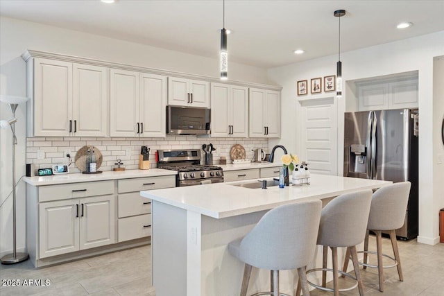 11951 W Wier Ave, Avondale, AZ 85323 - kitchen featuring stainless steel appliances, decorative backsplash, a kitchen breakfast bar, pendant lighting, and a center island with sink