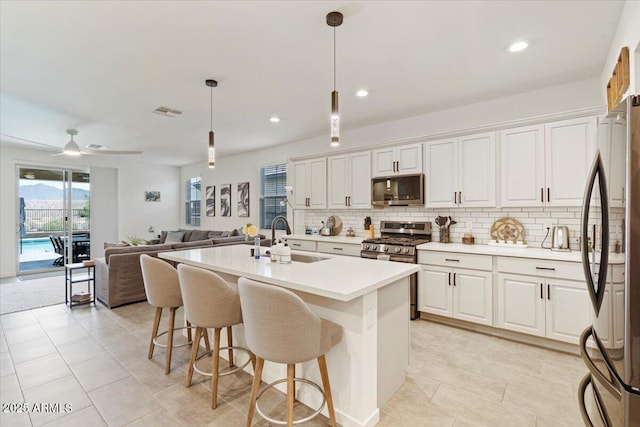11951 W Wier Ave, Avondale, AZ 85323 - kitchen with stainless steel appliances, open floor plan, white cabinets, tasteful backsplash, and recessed lighting