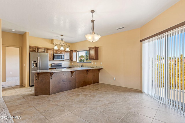 kitchen featuring kitchen peninsula, appliances with stainless steel finishes, a breakfast bar, light tile patterned floors, and hanging light fixtures