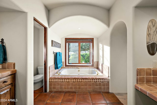 bathroom featuring vanity, a relaxing tiled tub, and toilet