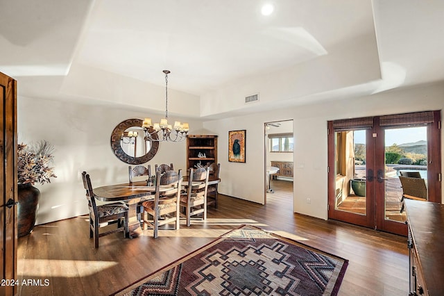 dining space with a notable chandelier, dark hardwood / wood-style flooring, french doors, and a tray ceiling