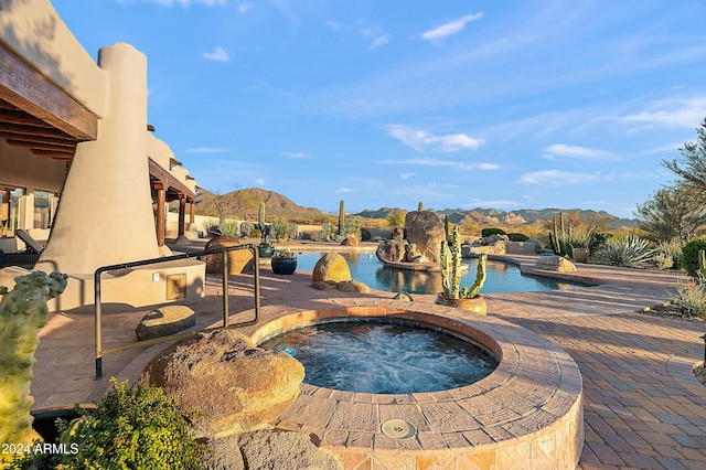 view of swimming pool featuring an in ground hot tub, a mountain view, and a patio