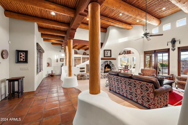 living room with beamed ceiling, a towering ceiling, ceiling fan, and wood ceiling