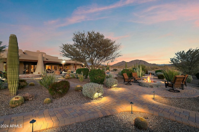 yard at dusk with a fire pit, a mountain view, and a patio area