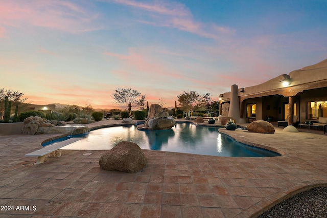 pool at dusk with a patio area