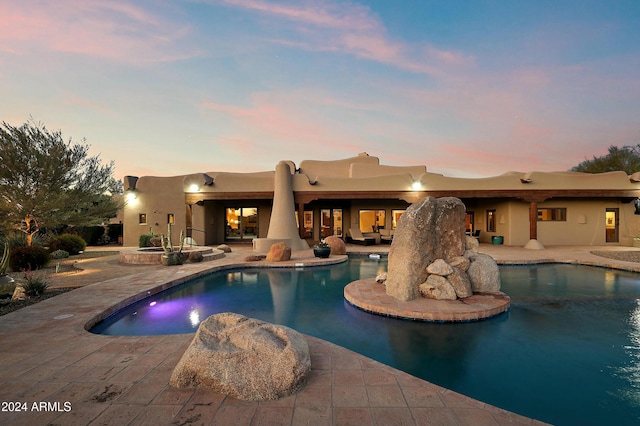 pool at dusk with a patio area