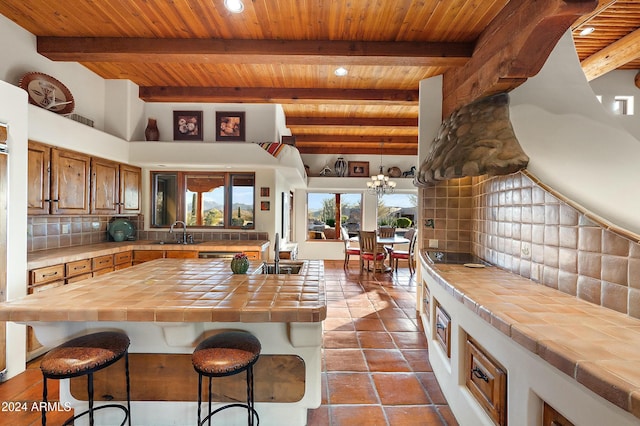 kitchen featuring tile counters, beam ceiling, sink, and backsplash