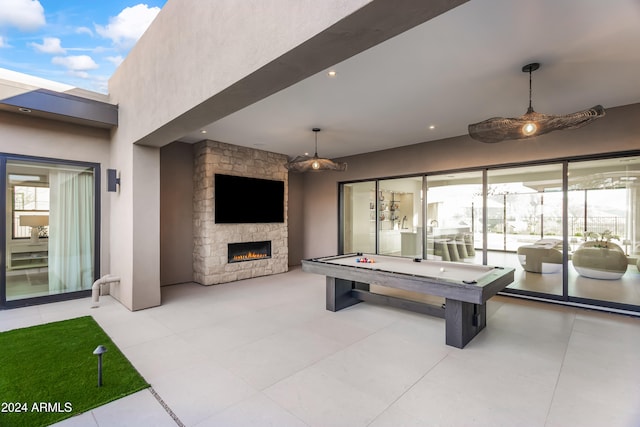 game room with an outdoor stone fireplace and light tile patterned flooring