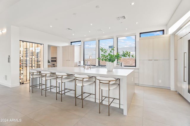 kitchen featuring a large island with sink, sink, a breakfast bar area, and light tile patterned floors