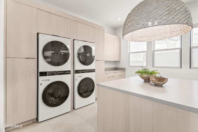 laundry room featuring stacked washer / drying machine, washing machine and clothes dryer, light tile patterned floors, and cabinets