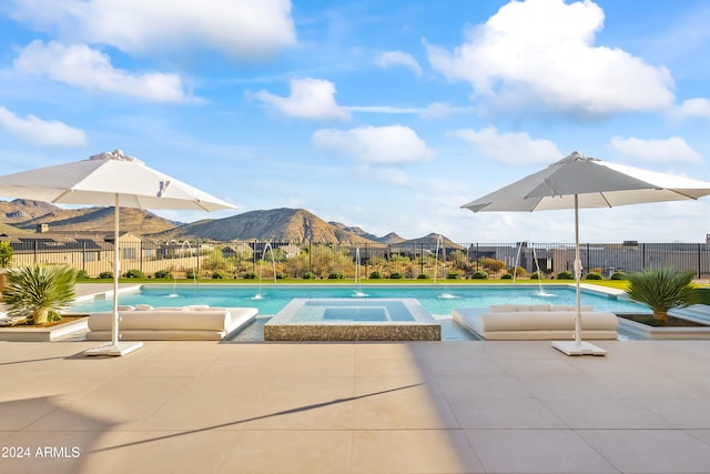 view of pool with an in ground hot tub, a mountain view, pool water feature, and a patio area