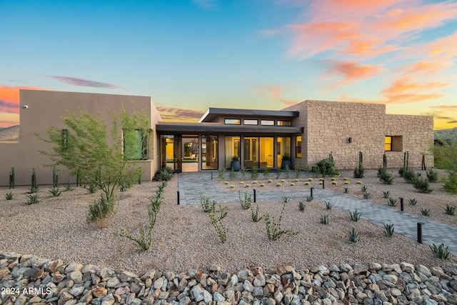 back house at dusk featuring a patio area