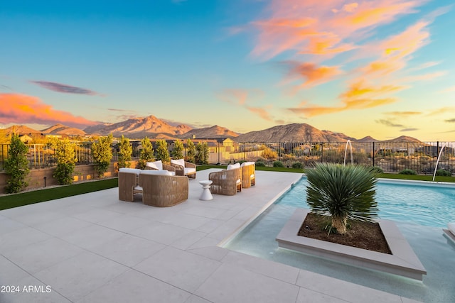 pool at dusk with a mountain view and a patio area