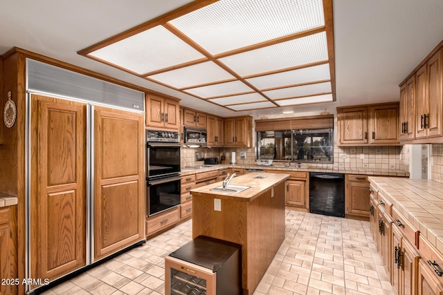 kitchen featuring a kitchen island, tasteful backsplash, sink, built in appliances, and tile counters