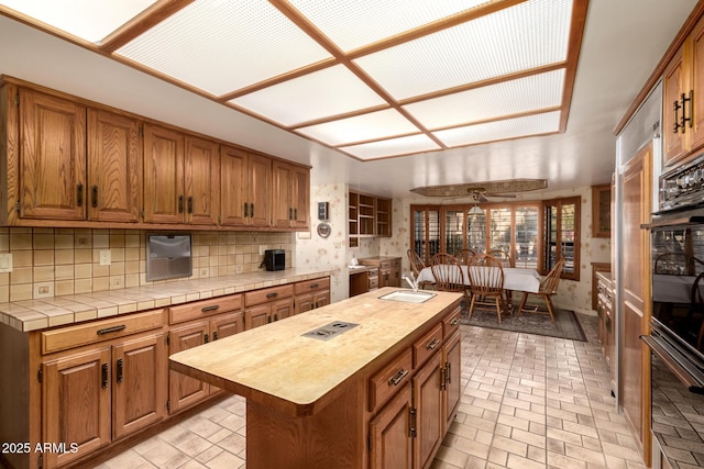 kitchen with a kitchen island with sink, sink, and decorative backsplash