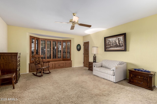 living area featuring light colored carpet and ceiling fan