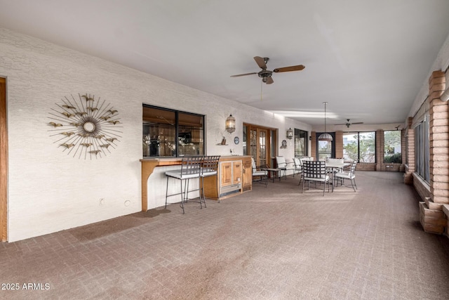 view of patio / terrace featuring a bar, ceiling fan, and french doors