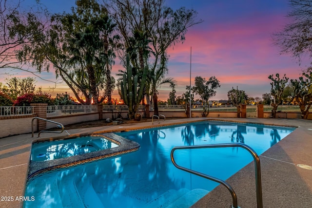 pool at dusk featuring an in ground hot tub and a patio area