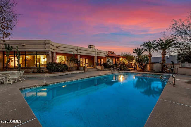 pool at dusk featuring a patio