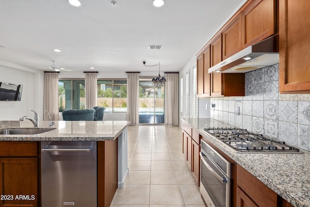 kitchen with sink, appliances with stainless steel finishes, light stone counters, and a wealth of natural light