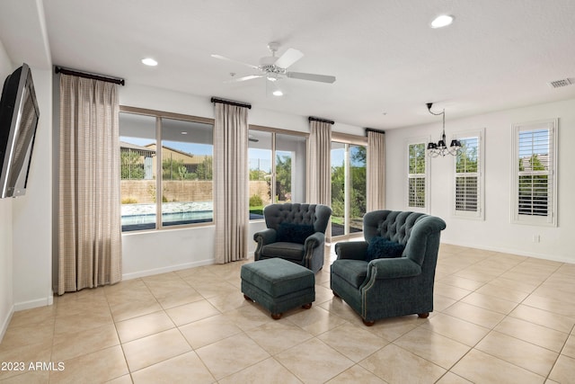 living area with ceiling fan with notable chandelier and light tile floors