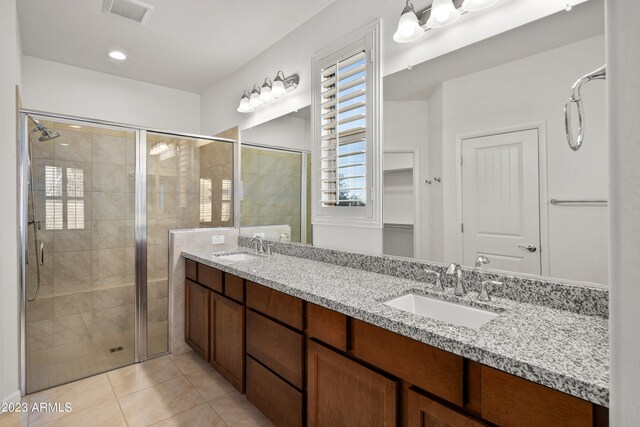 bathroom featuring dual vanity, tile flooring, and a shower with door