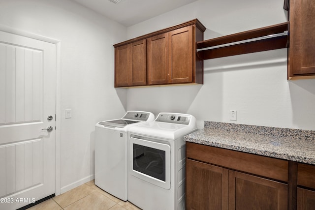 washroom with cabinets, light tile flooring, and washer and dryer