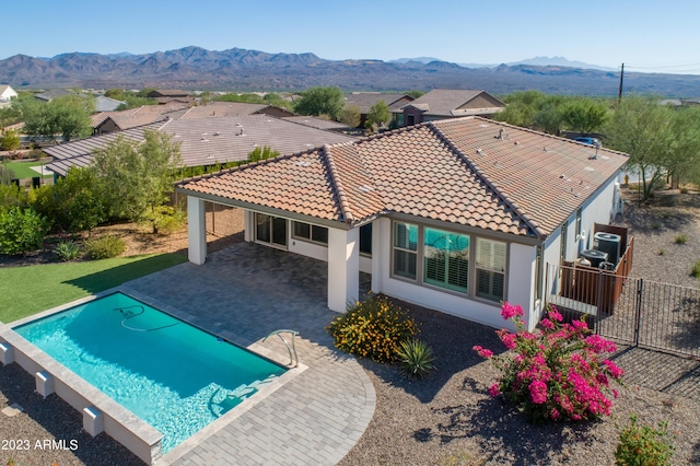 rear view of property featuring a fenced in pool, a patio area, and a mountain view