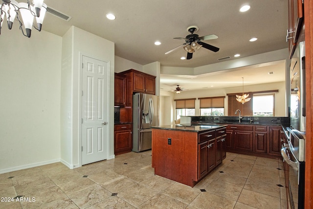 kitchen featuring ceiling fan with notable chandelier, a center island, kitchen peninsula, pendant lighting, and appliances with stainless steel finishes