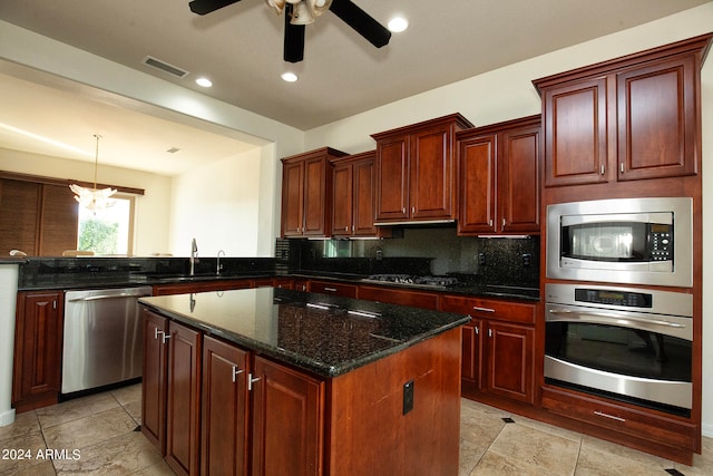 kitchen featuring sink, appliances with stainless steel finishes, dark stone counters, a center island, and decorative backsplash