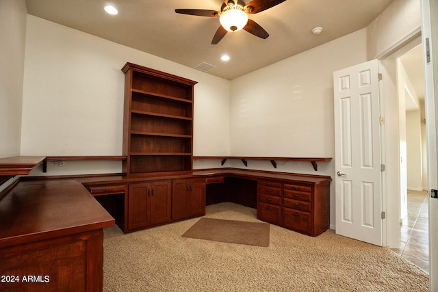 office space featuring built in desk, ceiling fan, and light colored carpet