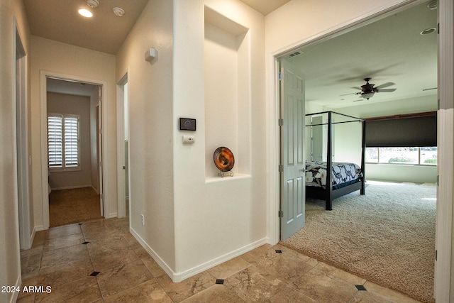 hallway with a wealth of natural light and light colored carpet