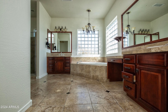 bathroom with a chandelier, vanity, and a relaxing tiled tub