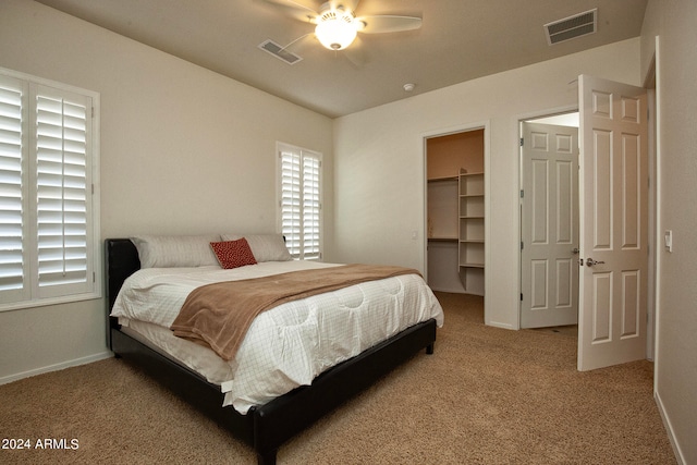 carpeted bedroom with a spacious closet, ceiling fan, and a closet