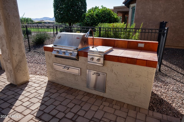 view of patio featuring area for grilling, a mountain view, and an outdoor kitchen