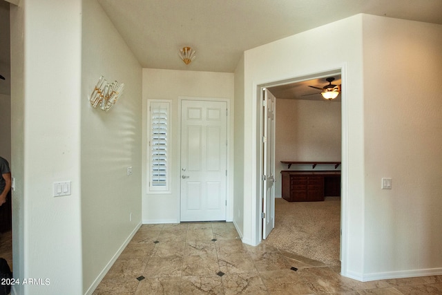 foyer entrance with ceiling fan and light carpet