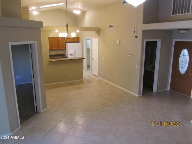 kitchen featuring white refrigerator with ice dispenser, high vaulted ceiling, an inviting chandelier, hanging light fixtures, and light tile patterned floors