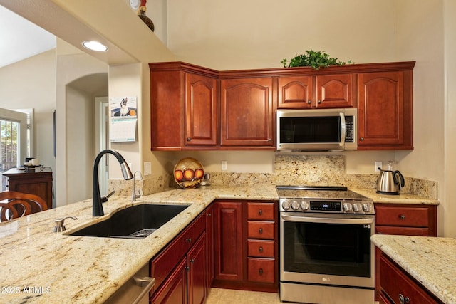 kitchen featuring appliances with stainless steel finishes, sink, and light stone counters