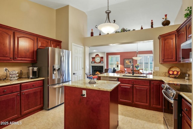 kitchen featuring sink, appliances with stainless steel finishes, hanging light fixtures, light stone countertops, and a kitchen island