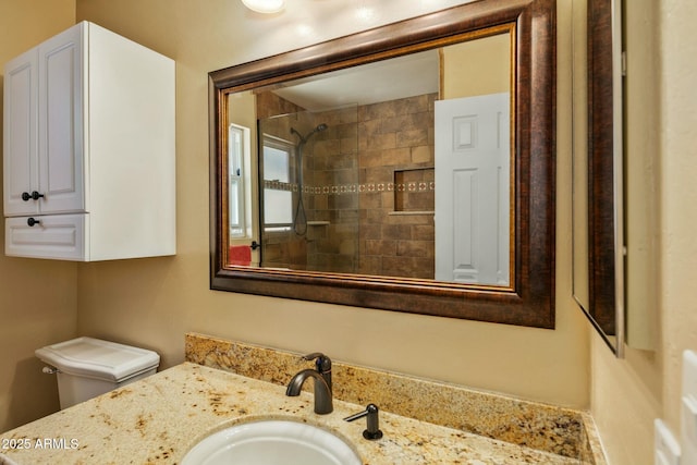 bathroom with vanity, a tile shower, and toilet