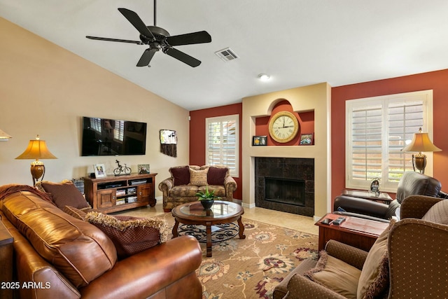 living room featuring a wealth of natural light, vaulted ceiling, a tile fireplace, and ceiling fan