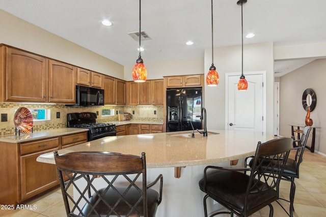 kitchen featuring light tile patterned floors, a sink, visible vents, black appliances, and tasteful backsplash