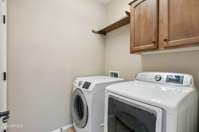washroom featuring washer and clothes dryer, cabinet space, and baseboards
