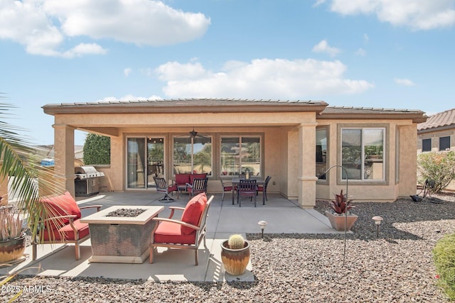 rear view of house featuring a patio area, stucco siding, a tiled roof, a ceiling fan, and an outdoor fire pit