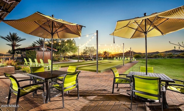view of community with a lawn, outdoor dining area, and fence