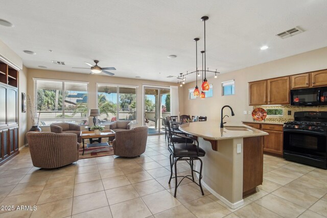 kitchen featuring a sink, brown cabinets, black appliances, visible vents, and open floor plan